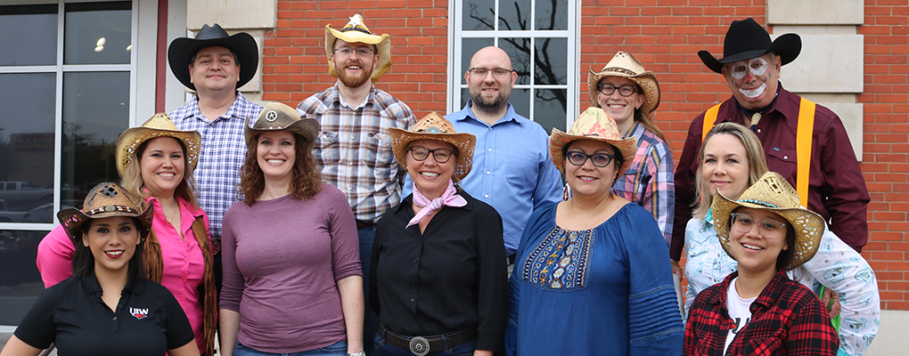 Employees dressed in Western wear gather for a photo