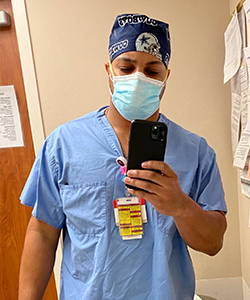 Juwan Jiles poses for a photo in his nursing scrubs and face mask