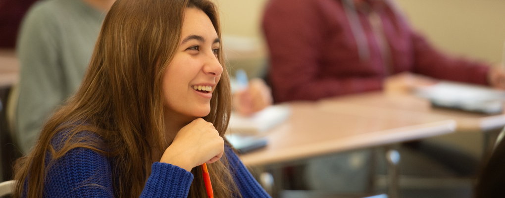 A student sits in class and smiles