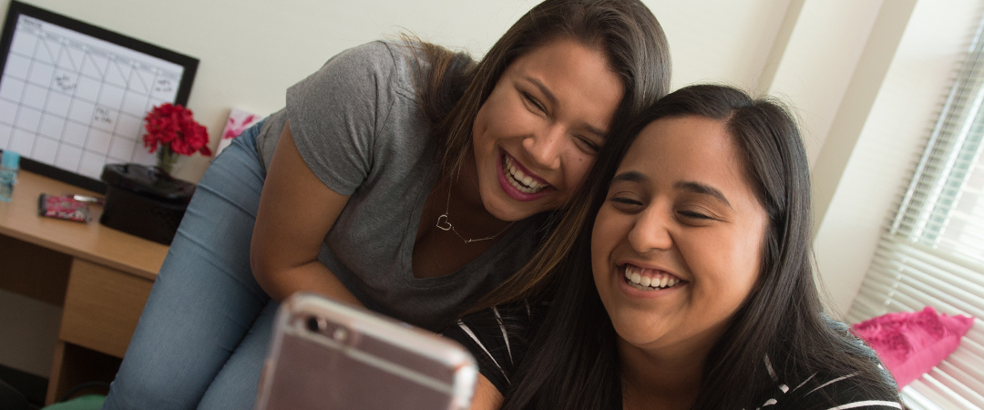 Student smiling while looking at a cellphone