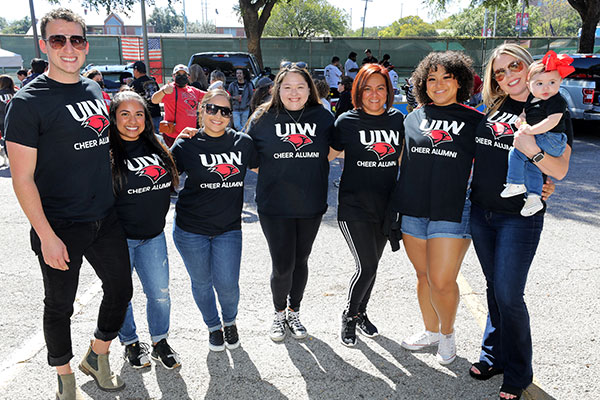 Seven cheer alumni in a group smiling at the camera