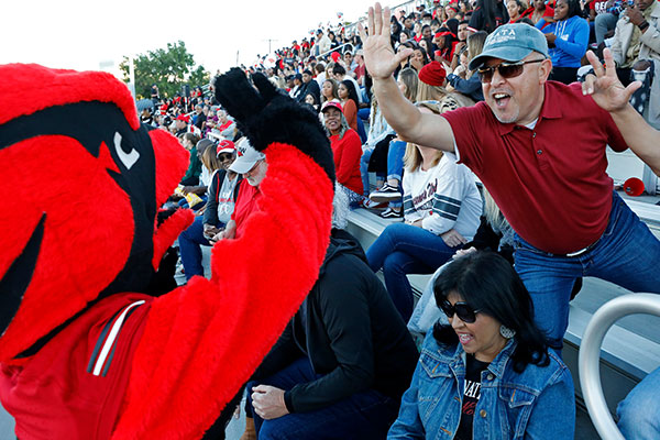 Red mascot giving high five to fan at game