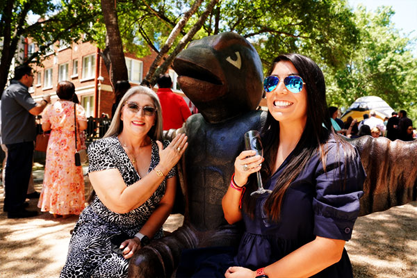 Two alumni showing their rings with Red mascot statue