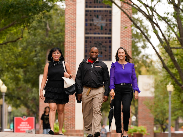 Three students walking across UIW's main campus