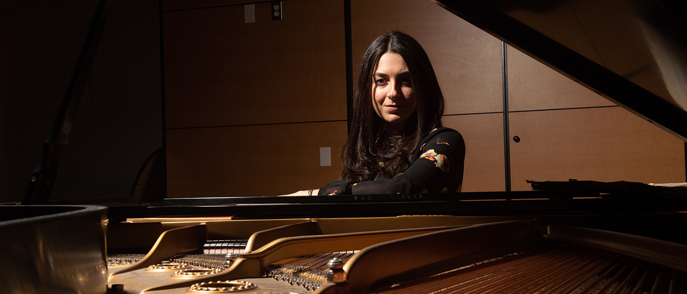 Lady standing behind an open piano