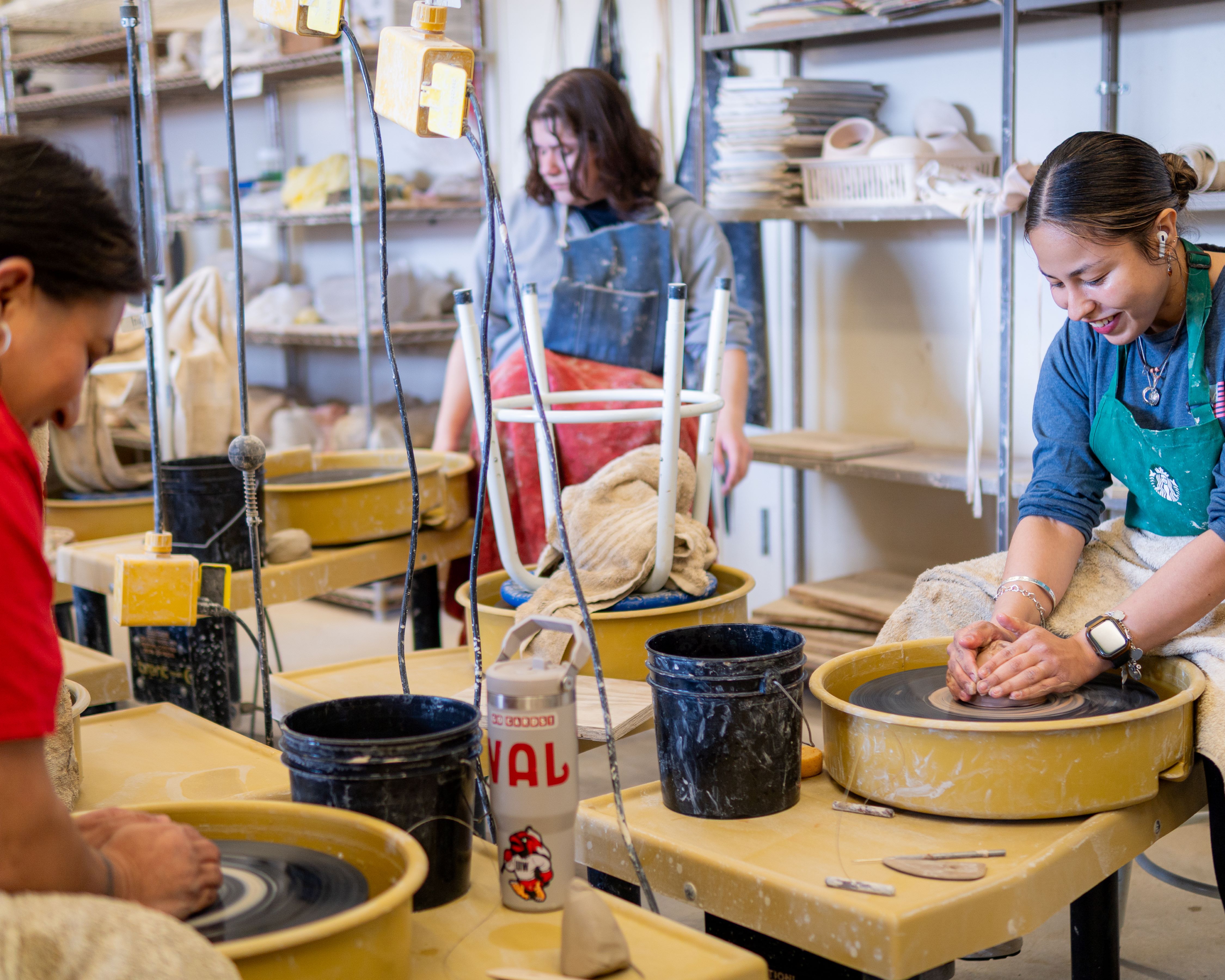 Students centering their clay on a ceramics wheel
