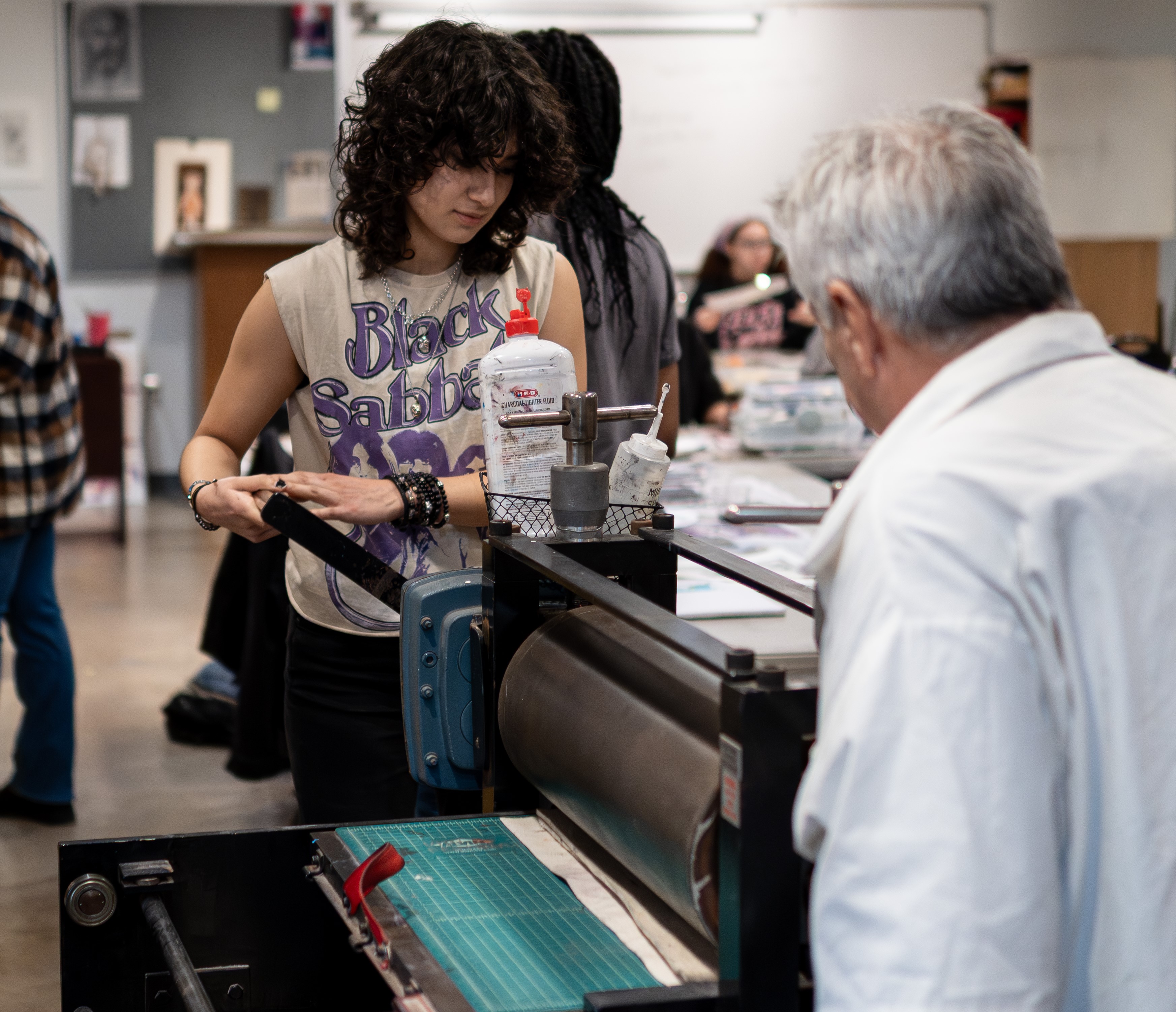 Professor instructing a student to use a printmaking press