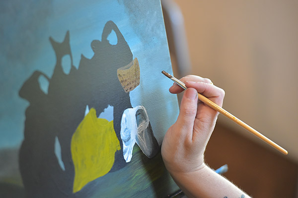 Closeup of a student's hand working on a painting