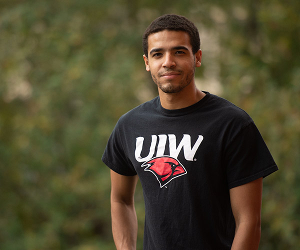 Student standing outside on campus with trees in the background
