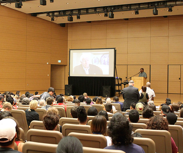Speaker giving a presentation on his book to a full auditorium