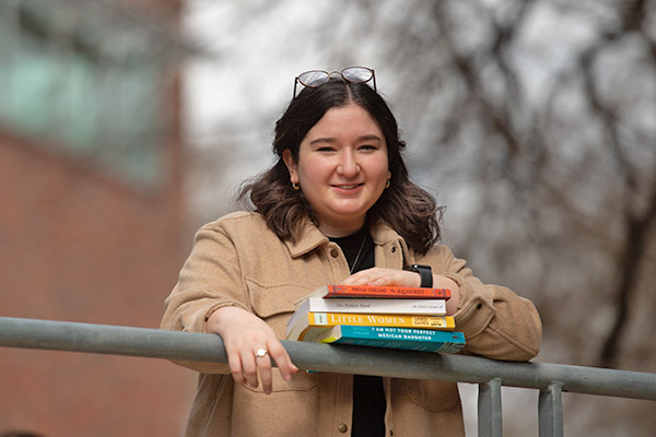 English student with several books smiling at the camera