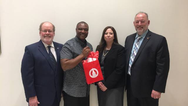Group photo of Anthony Graves holding a UIW gift bag with CHASS staff.