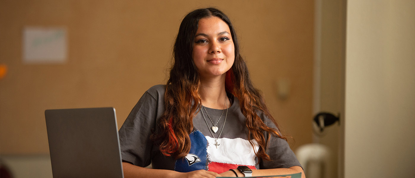 History student sitting at her desk with a book and laptop