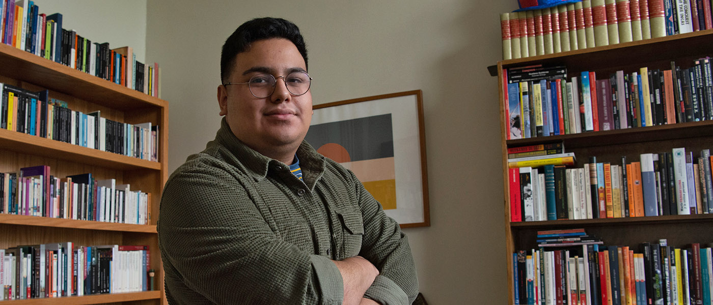 Spanish student with arms crossed standing in front of bookshelves filled with Spanish literature