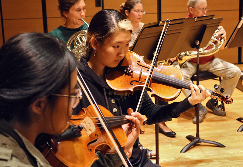 Closeup of music students in violin section of the orchestra