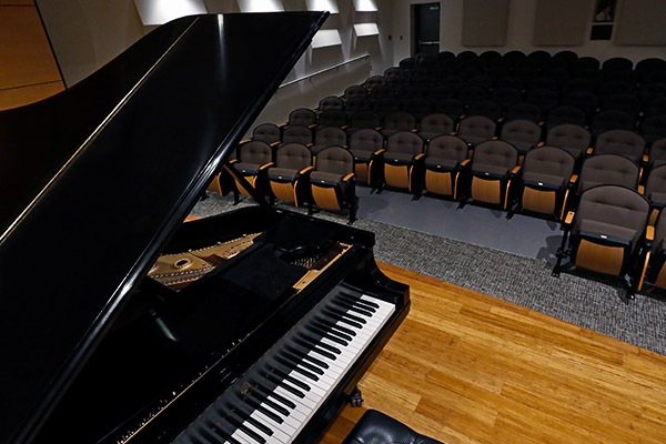 Photo of piano on stage in empty recital hall