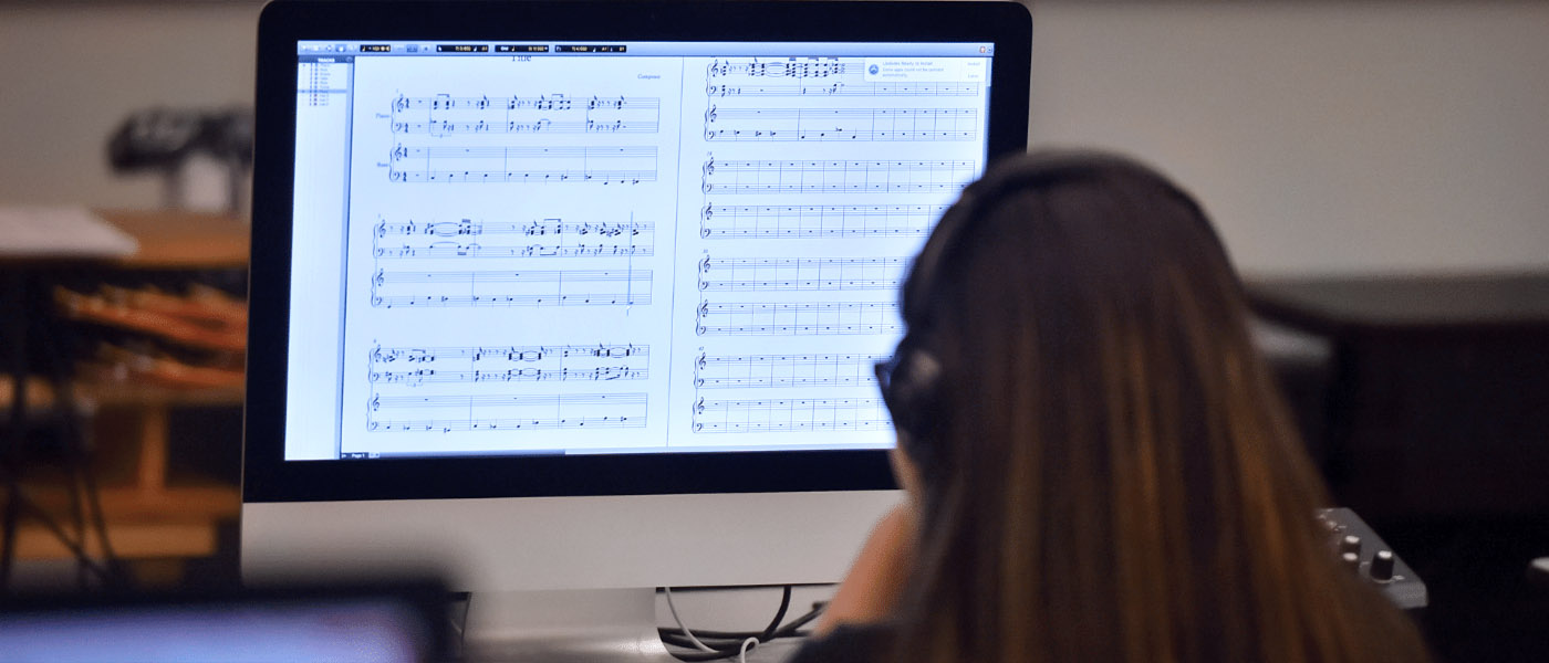 female student sitting in front of computer looking a music notes