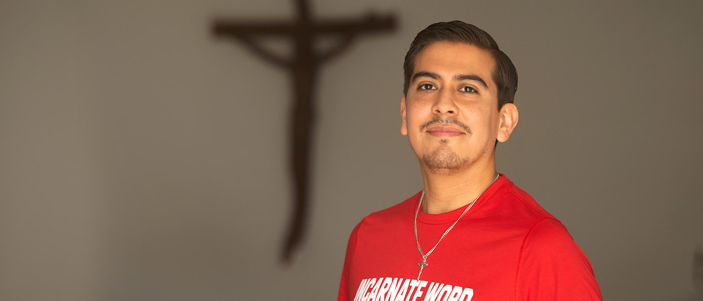 Pastoral Institute student in a chapel posing in front of a wall with a crucifix on it