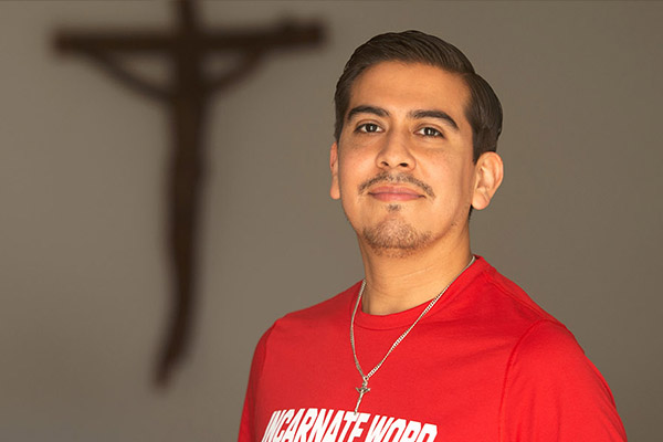 Pastoral Institute student posing in front of a wall with a crucifix on it