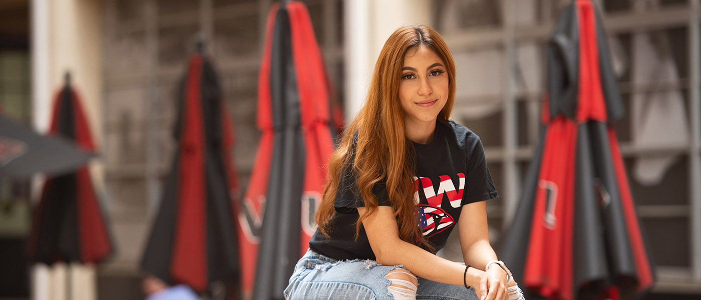 Smiling student sitting on a table at an outdoor courtyard