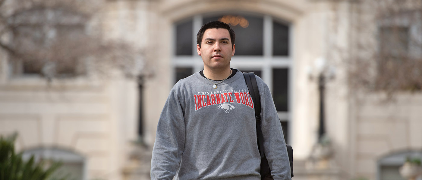 Student walking on campus with administration building in the background