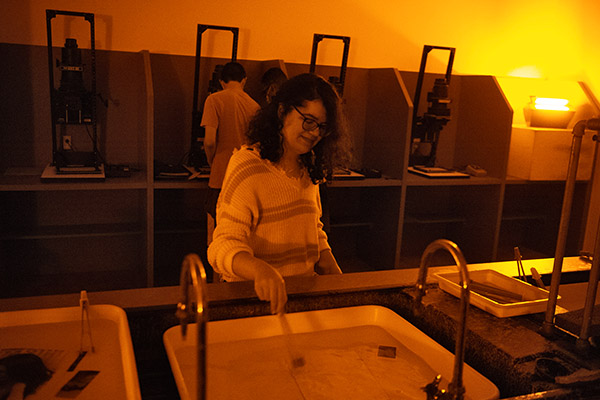 Photography students in a dark room developing photographs