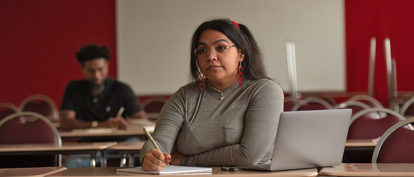 Student sitting at her desk writing on a notebook during class
