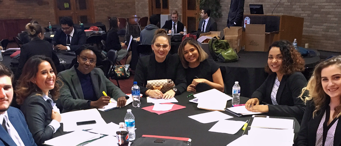 Smiling moot court team members sitting at a table preparing for competition