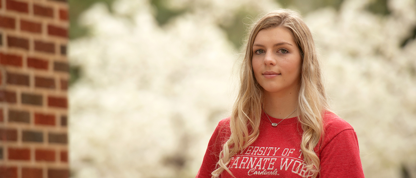 Close up of a student on campus with blooming flowers in the background