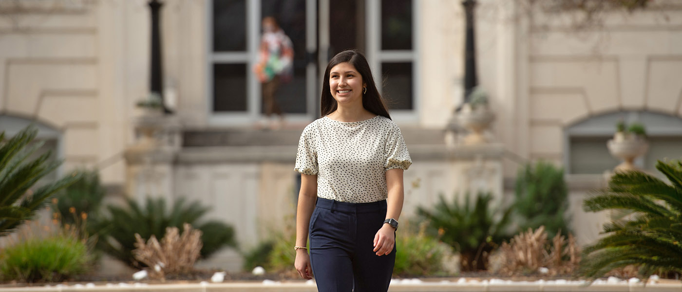 Student walking on campus with the administration building in the background