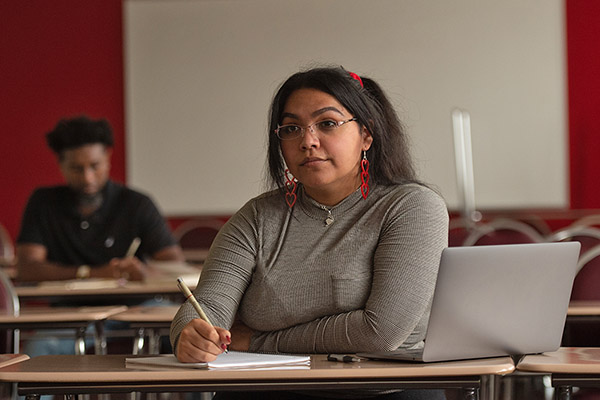 Student at her desk writing on a notebook during class