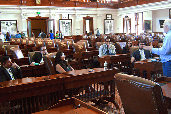 Students sitting in the local house of representatives floor as a professor gives a lesson on the legislative process