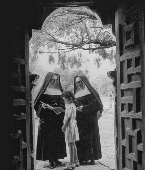 CCVI sisters black and white image, standing in a doorway with a child.