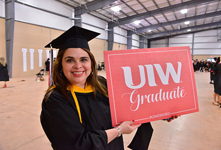 Student holding a UIW graduate sign