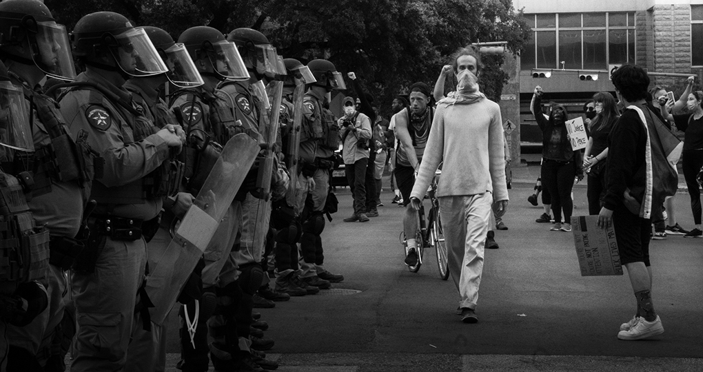 protestors marching in front of police in riot gear