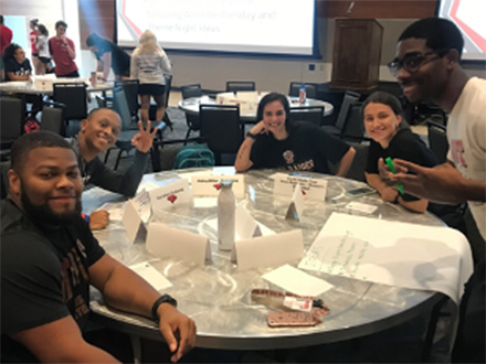 five students posing around a conference table