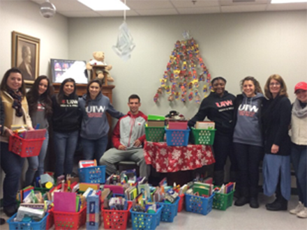 student athletes posing around a christmas tree surrounded by presents