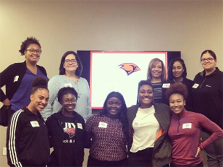 a group of student athletes posing in front of a presentation screen