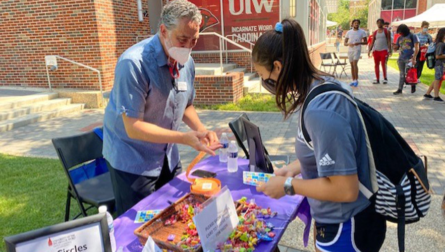 Students at a hand out table in the UIW quad