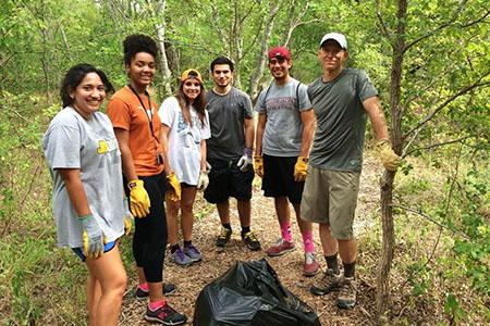 students in the woods with a trash bag and shovel