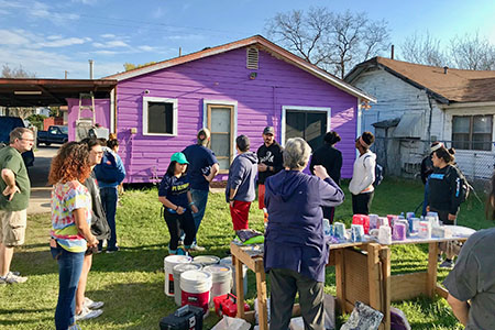 students working outdoors in front of a purple house