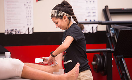 female athletic trainer taping student athlete