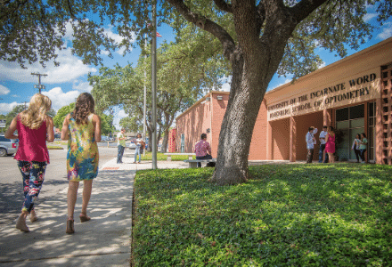 Exterior shot of the Optometry building with students walking towards the doors