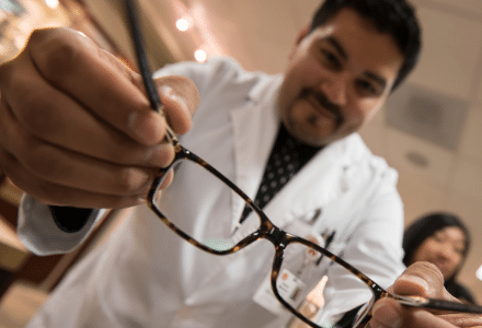 Male optometry student holding up a pair of black frames