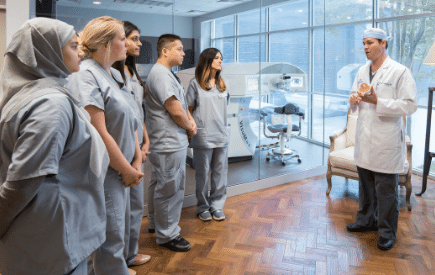 Optometry students in scrubs listening to a faculty member in a lecture