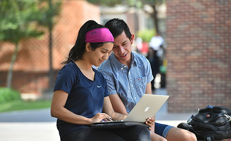 Two students on laptop on campus