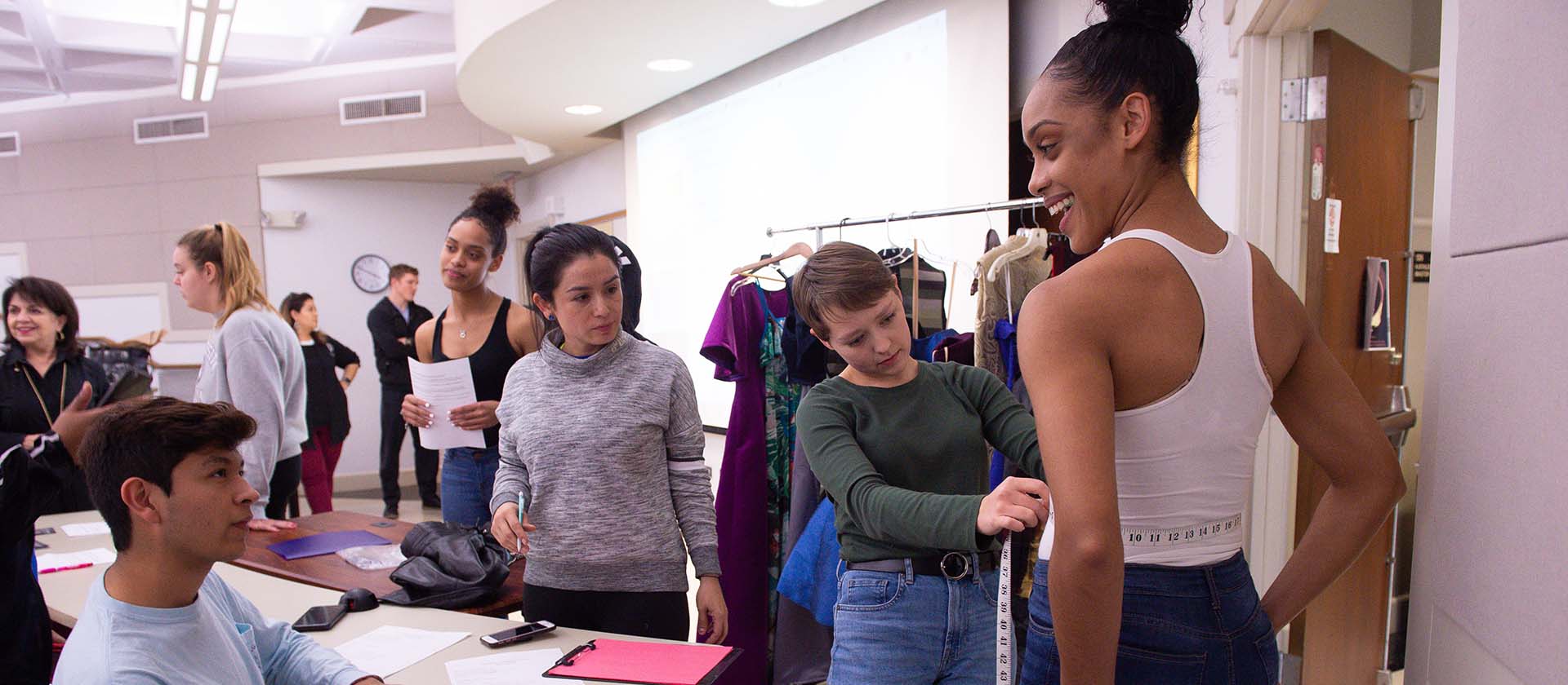 Group of students in fashion program measuring sizes and discussing latest designs