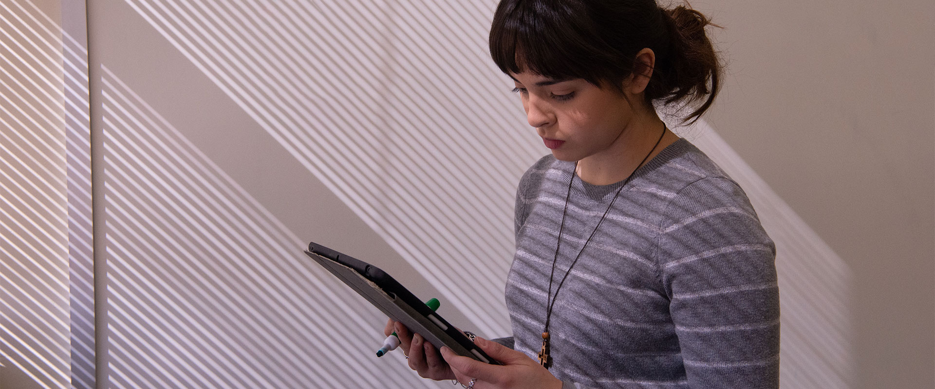 Female student standing in front of white board while looking at her tablet