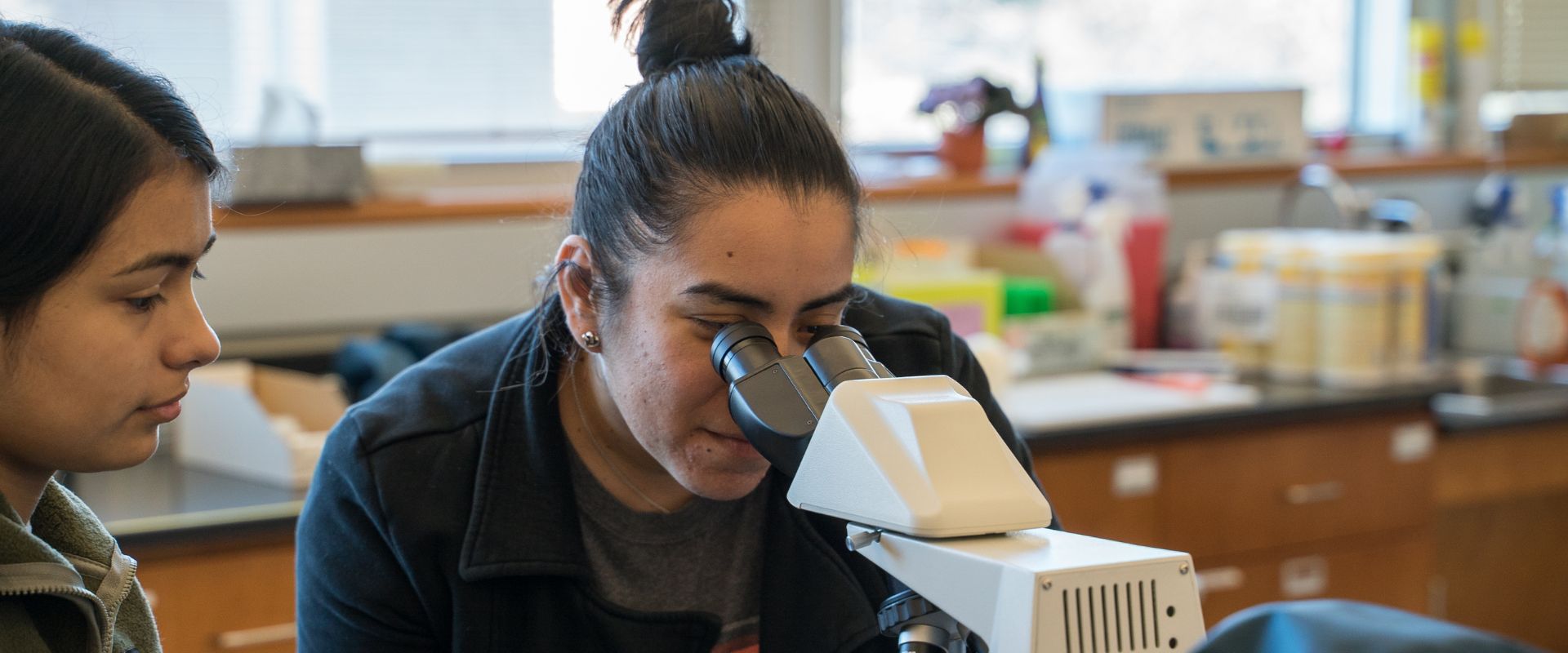 Student looking through the lens of a microscope