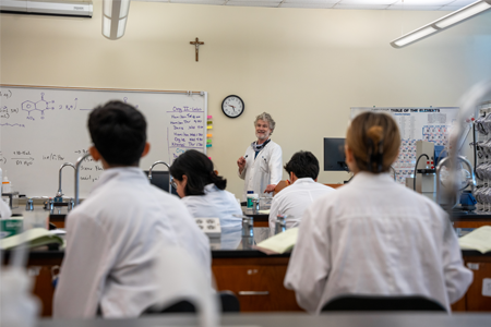 Student wearing a lab coat and safety gear conducting a chemistry experiment in a laboratory